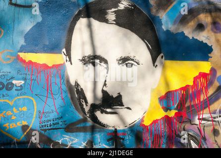 Prag, Repubblica Ceca. 23rd Mar 2022. Sul cosiddetto muro di John Lennon a Praga, una persona sconosciuta ha descritto il presidente russo Vladimir Putin come Adolf Hitler in vista della guerra in Ucraina. Sopra di esso, il 23 marzo 2022, è scritto in ceco lo slogan 'valka je vul' - letteralmente 'la guerra è un horndog'. Ciò che si intende con questo è che la guerra è assurdità. Il Muro Lennon nella città minore di Praga è stato inscritto con messaggi politici in continuo cambiamento dal 1980s. Ricorda il cantante dei Beatles John Lennon, una delle icone del movimento di pace. Credit: Michael Heitmann/dpa/Alamy Live News Foto Stock