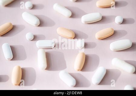 Pillole diverse, capsule di vitamina su sfondo rosa pastello. Supplementi dietetici di sostegno per la salute. Foto Stock