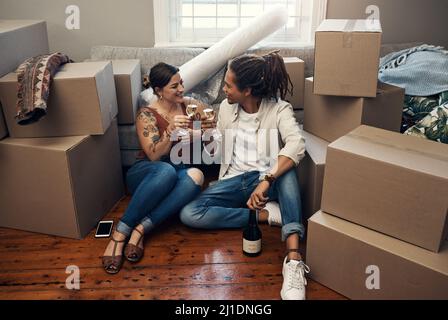 Lo meritiamo davvero, babe. Scatto di una giovane coppia felice che ha champagne per celebrare la loro nuova casa. Foto Stock