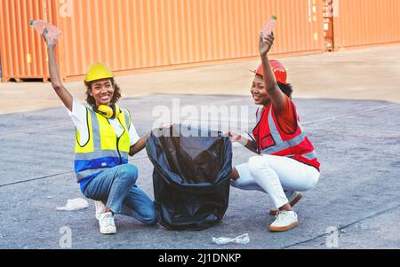 African american donna caposquadra o operaio di manutenzione messo su caschi di sicurezza mano che tiene garbage nero sacchetto e la collaborazione che mette il wast di garbage di plastica Foto Stock