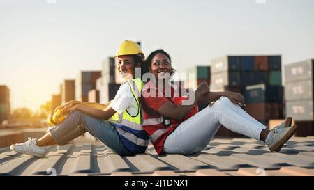 African american Woman Foreman o ispettore suppervisor seduti dietro l'altro su vecchio serbatoio di carico al deposito di carico o cantiere container po Foto Stock