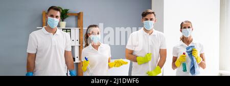 Professional Office Cleaning Janitor Team in maschere uniformi e facciali Foto Stock