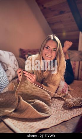 Il lavoro a maglia non è solo per le donne anziane. Ritratto di una giovane donna a maglia mentre si rilassa nella sua camera da letto a casa. Foto Stock