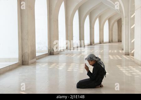 Dhaka, Dhaka, Bangladesh. 25th Mar 2022. Un bambino prega alla Moschea Nazionale di Baiitul Mukarram a Dhaka, Bangladesh. La Moschea Nazionale del Bangladesh, conosciuta come Baitul Mukarram o la Casa Santa in inglese, è una delle 10 moschee più grandi del mondo e può ospitare fino a 40.000 persone, anche nello spazio aperto esterno. La moschea ha diverse caratteristiche architettoniche moderne e allo stesso tempo conserva i principi tradizionali dell'architettura Mughal, che da qualche tempo è stata dominante nel subcontinente indiano. (Credit Image: © Joy Saha/ZUMA Press Wire) Credit: ZUMA Press, Inc./ Foto Stock