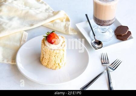 Torta di tronchi di fragola su sfondo bianco. Con cioccolata calda sul lato. Primo piano Foto Stock