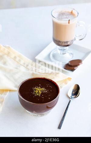 Budino di cioccolato o dessert sorpente su sfondo bianco. Con cioccolata calda sul lato. Primo piano Foto Stock