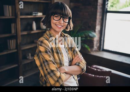 Ritratto di affascinante buon umore graziosa donna d'affari con le braccia ripiegate che indossano gli occhiali rilassarsi a casa al chiuso Foto Stock