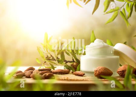 Crema idratante con estratto di mandorle su tavola di legno in natura. Vista frontale. Composizione orizzontale. Foto Stock