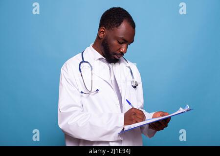 Ritratto di medico medico in camice bianco di laboratorio che tiene appunti scrivere sulla cartella paziente in consultazione clinica. Medico professionista con stetoscopio prendere appunti guardando la storia medica. Foto Stock