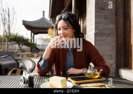 Studente universitario cinese che gusta il tè pomeridiano nel caffè sul marciapiede - foto di scorta Foto Stock