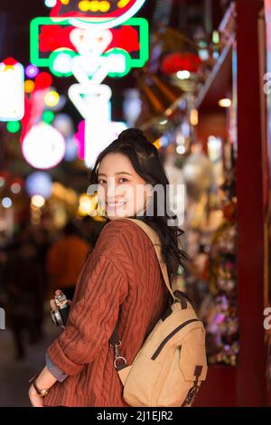 Donna colletto bianco con una macchina fotografica che passeggera il mercato notturno - foto di scorta Foto Stock