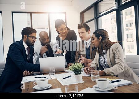 Le collaborazioni di affari sono che cosa theyre il la cosa migliore a. Girato di un gruppo di giovani uomini d'affari che utilizzano un notebook insieme durante una riunione in un ufficio moderno. Foto Stock