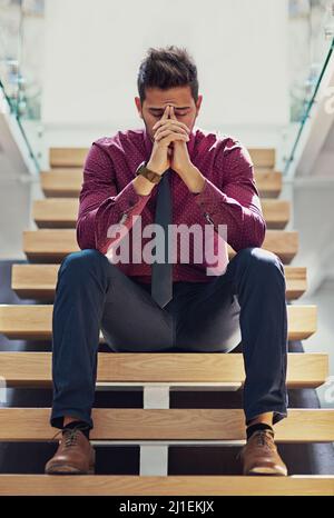 Le cose dovranno migliorare di questo.... Scatto di un giovane uomo d'affari che guarda stressato mentre si siede sulle scale. Foto Stock