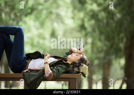 Giovane fotografo femmina che si trova e riposa su panca - foto di scorta Foto Stock