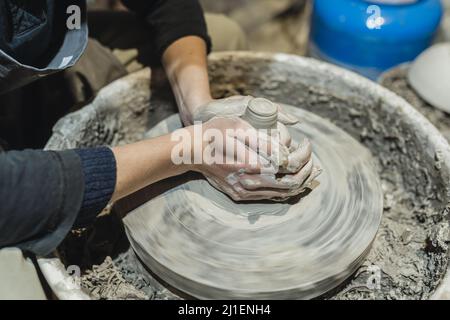 Le mani di Potter si avvicinano, sulla ruota del vasaio, in argilla, facendo ceramica Foto Stock