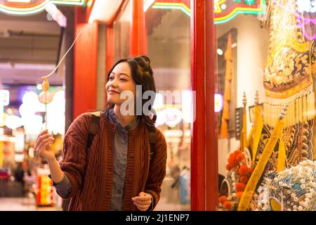 Giovane studentessa universitaria femminile ammirando la figura di zucchero di calabash ad un mercato notturno a Pechino - foto di scorta Foto Stock