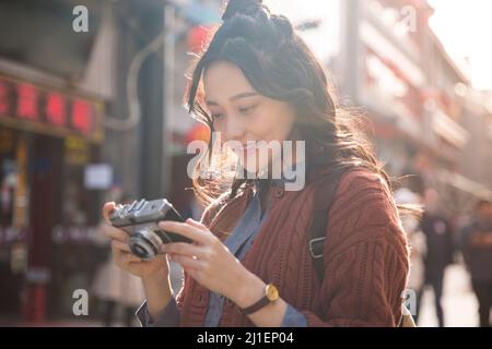 Donna zaino in spalla scattando foto in stile classico strada pedonale - foto di scorta Foto Stock