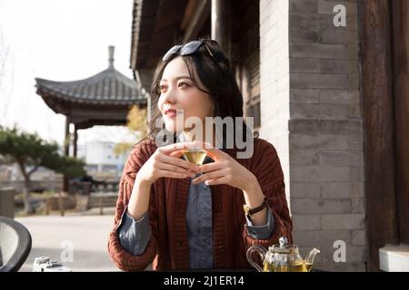 Studente universitario cinese che gusta il tè pomeridiano nel caffè sul marciapiede - foto di scorta Foto Stock