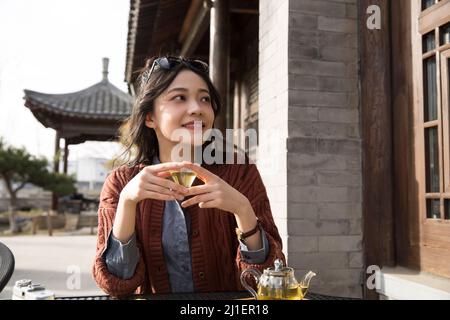 Studente universitario cinese che gusta il tè pomeridiano nel caffè sul marciapiede - foto di scorta Foto Stock