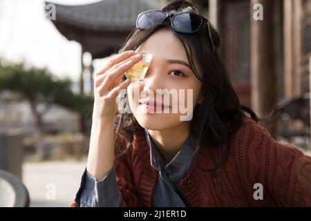 Studente universitario cinese che gusta il tè pomeridiano nel caffè sul marciapiede - foto di scorta Foto Stock