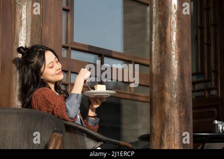 Donna cinese con colletto bianco che gusta il tè pomeridiano nel caffè sul marciapiede - foto di scorta Foto Stock