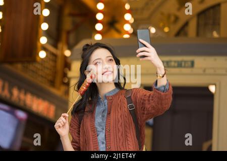 Giovane ragazza del college che prende un selfie su una strada pedonale vecchio stile - foto di scorta Foto Stock