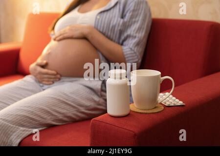 Donna incinta e diverse pillole a casa Foto Stock