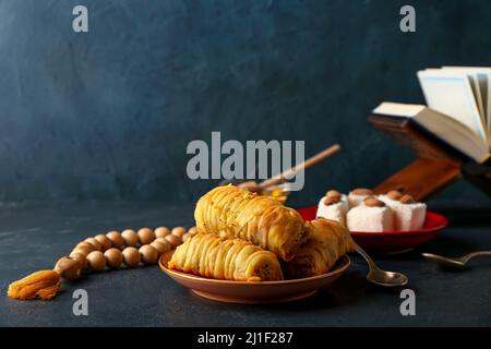 Gustoso baklava turco con tasbih su sfondo scuro Foto Stock