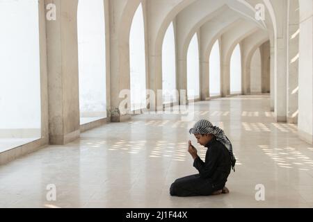 Un bambino prega alla Moschea Nazionale di Baiitul Mukarram a Dhaka, Bangladesh. La Moschea Nazionale del Bangladesh, conosciuta come Baitul Mukarram o la Casa Santa in inglese, è una delle 10 moschee più grandi del mondo e può ospitare fino a 40.000 persone, anche nello spazio aperto esterno. La moschea ha diverse caratteristiche architettoniche moderne e allo stesso tempo conserva i principi tradizionali dell'architettura Mughal, che da qualche tempo è stata dominante nel subcontinente indiano. (Foto di Joy Saha / Pacific Press) Foto Stock