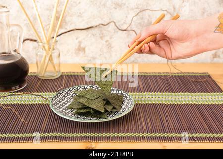 Donna che mangia gustosi fogli di alghe al tavolo Foto Stock