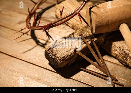 Corona di spine con croce in legno, mazzuolo e unghie su sfondo in legno Foto Stock