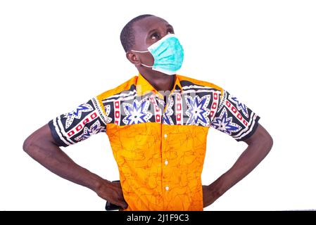 bel giovane uomo che indossa una maschera medica, che guarda in su mentre tiene le mani sui fianchi. Foto Stock