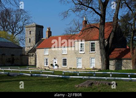 Cottages e All Saints Church nel villaggio di Hovingham nel distretto di Ryedale, North Yorkshire, Inghilterra Regno Unito Foto Stock