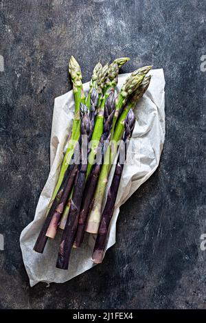 Asparagi bianchi, porpora, verdi grezzi su carta da imballaggio. Concetto di cibo crudo. Foto Stock