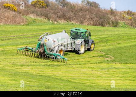 Spandimento di liquami con barre di dribble trainate dal trattore in Irish Farm Foto Stock