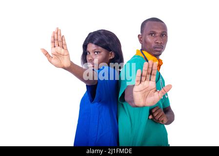 medico di sesso maschile con infermiere in piedi indietro in uniforme mostrando stop gesture con le mani in ospedale. Foto Stock