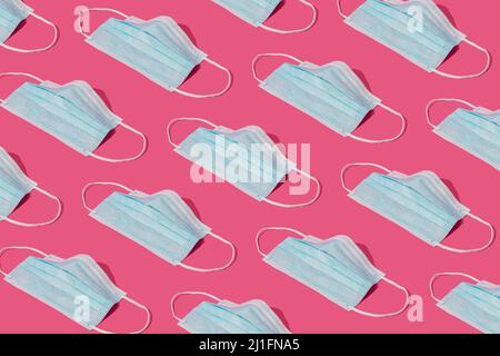 Modello realizzato con maschere chirurgiche mediche per la prevenzione di Coronavirus per la protezione da virus corona. Fondo globale di concetto di pandemia. Backgroun rosa alla moda Foto Stock