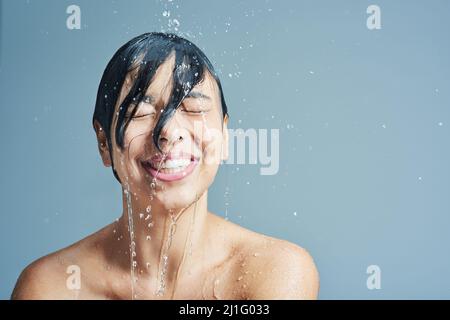 Svegliati con la sensazione rinfrescante dell'acqua. Scatto di una giovane donna che ha una doccia rinfrescante su sfondo blu. Foto Stock