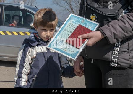 Una madre con documenti di identificazione e suo figlio cerca informazioni dopo essere entrato in Moldavia. Palanca è il confine più vicino alla città di Odessa, Ucraina. Questa piccola città è l'ultimo punto a sud della Moldavia prima di attraversare il territorio ucraino. Da quando è iniziato il conflitto armato, sono entrate circa 175.000 persone secondo le cifre del governo moldavo. Quando le persone entrano nel paese hanno la possibilità di rifugiarsi in campi profughi che il governo e le organizzazioni internazionali hanno creato per l'emergenza umanitaria, ma la maggior parte cercano di trasferirsi in altri paesi al centro Foto Stock