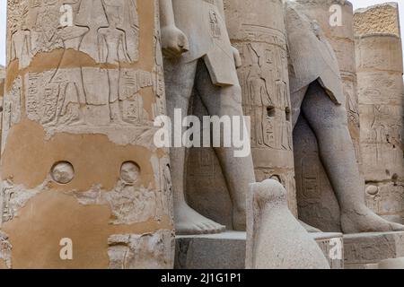 Gambe di statue tra colonne del cortile di Rameses II, Tempio di Luxor Foto Stock