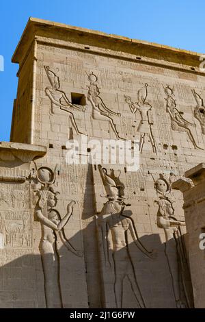 Sculture di Hathor, Iside e Horus sulla torre orientale del primo pilone del Tempio di Iside a Filae Foto Stock