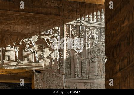 Sculture in bassorilievo in un'asta di luce solare nel Tempio di Iside a Philae Foto Stock