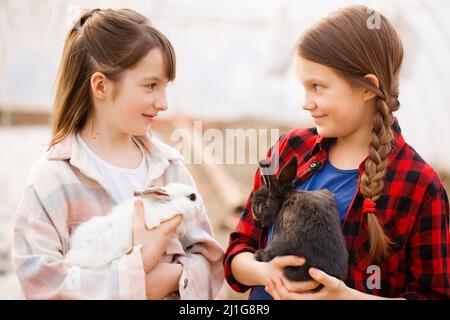 Due ragazze che tengono conigli nelle loro mani. Concetto di Pasqua Foto Stock