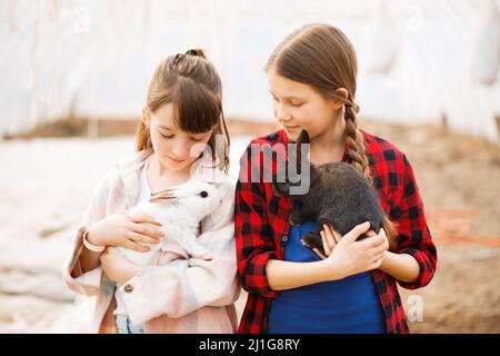 Due ragazze che tengono conigli nelle loro mani. Concetto di Pasqua Foto Stock