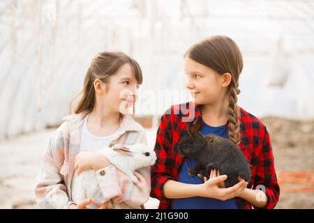 Due ragazze che tengono conigli nelle loro mani. Concetto di Pasqua Foto Stock