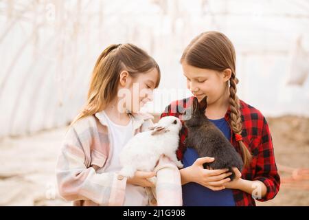 Due ragazze che tengono conigli nelle loro mani. Concetto di Pasqua Foto Stock