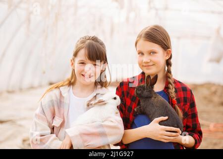 Due ragazze che tengono conigli nelle loro mani. Concetto di Pasqua Foto Stock