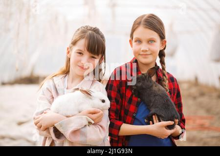 Due ragazze che tengono conigli nelle loro mani. Concetto di Pasqua Foto Stock