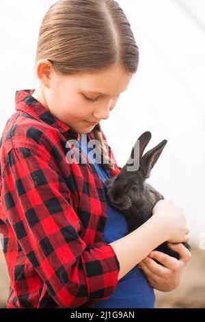 Ritratto di una ragazza con un coniglio nero nelle sue mani. Concetto di Pasqua Foto Stock