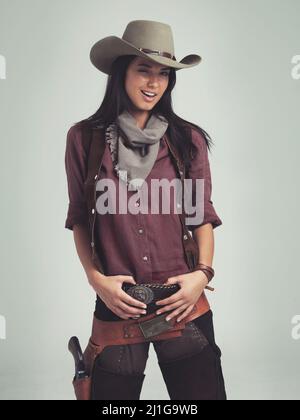 Ehi cowboy Scatto corto di una giovane donna attraente in abbigliamento cowboy. Foto Stock